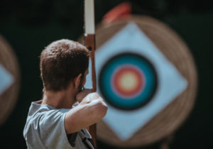 man performing archery in countryside stag activities